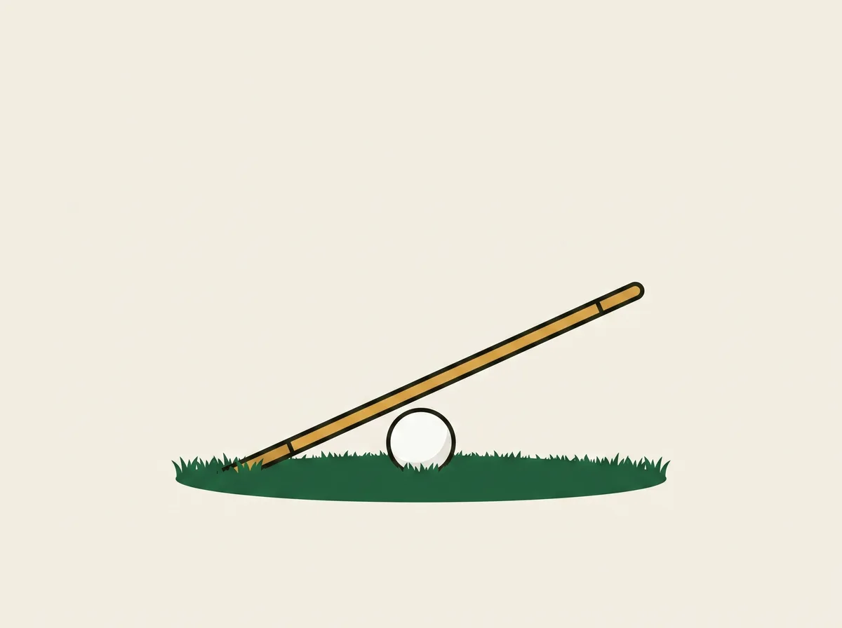 A golf ball on grass with an alignment stick planted in the ground beyond it and leaning over it